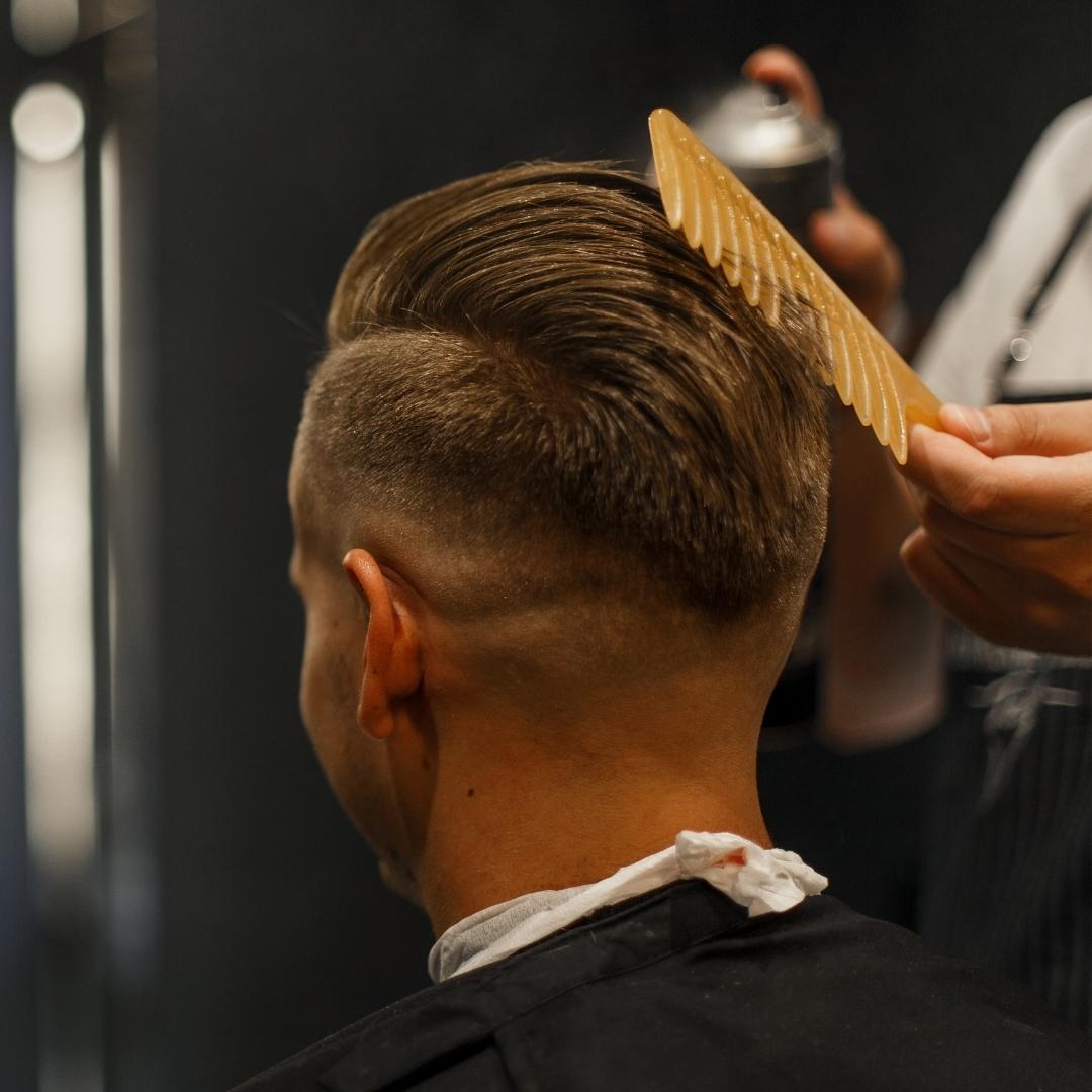 Barber spraying product into client's hair